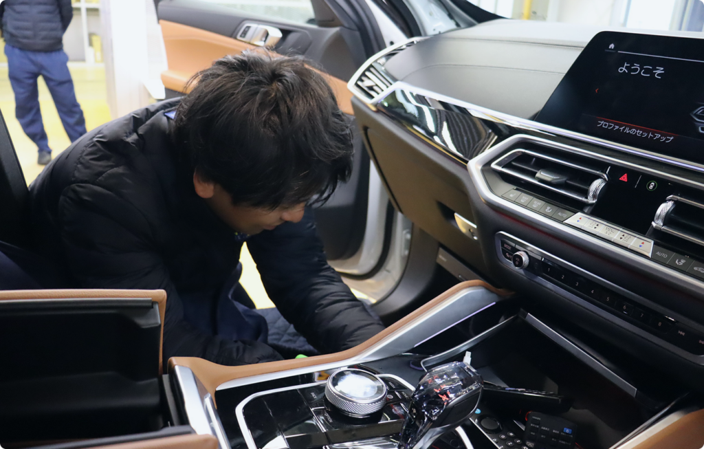 車の内装に機器を取り付けている技術スタッフの作業風景